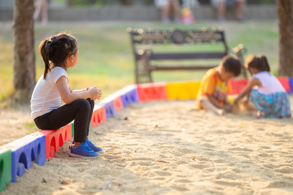 Petite fille regardant les autres enfants jouer