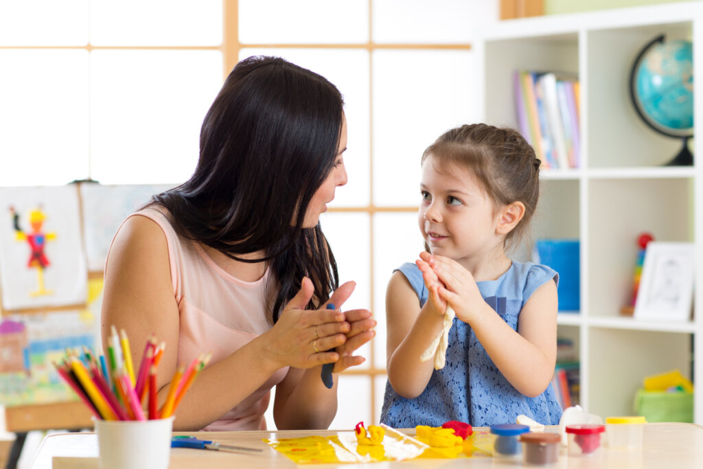 Madre hablando con su hija mientras hacen formas con plastilina