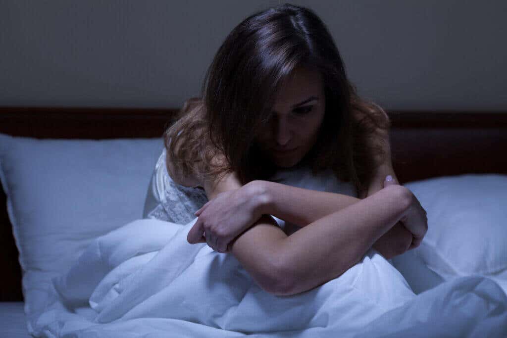 Mulher acordada na cama e preocupada