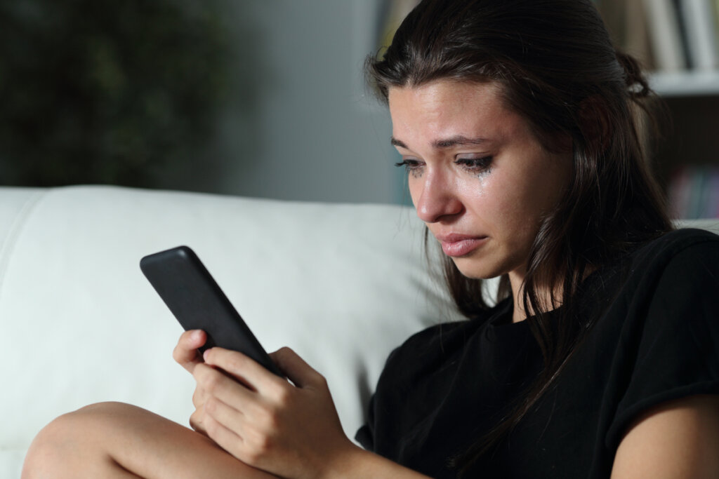 Chica triste mirando el móvil