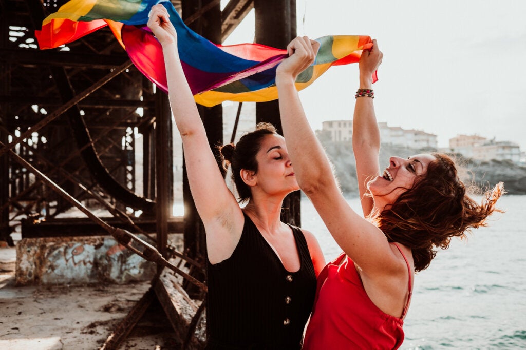 Duas mulheres lésbicas com uma bandeira do movimento LGBTQIA+