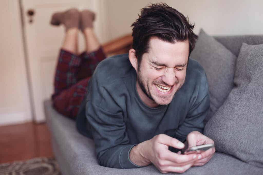Mężczyzna śmiejący się z telefonem komórkowym
