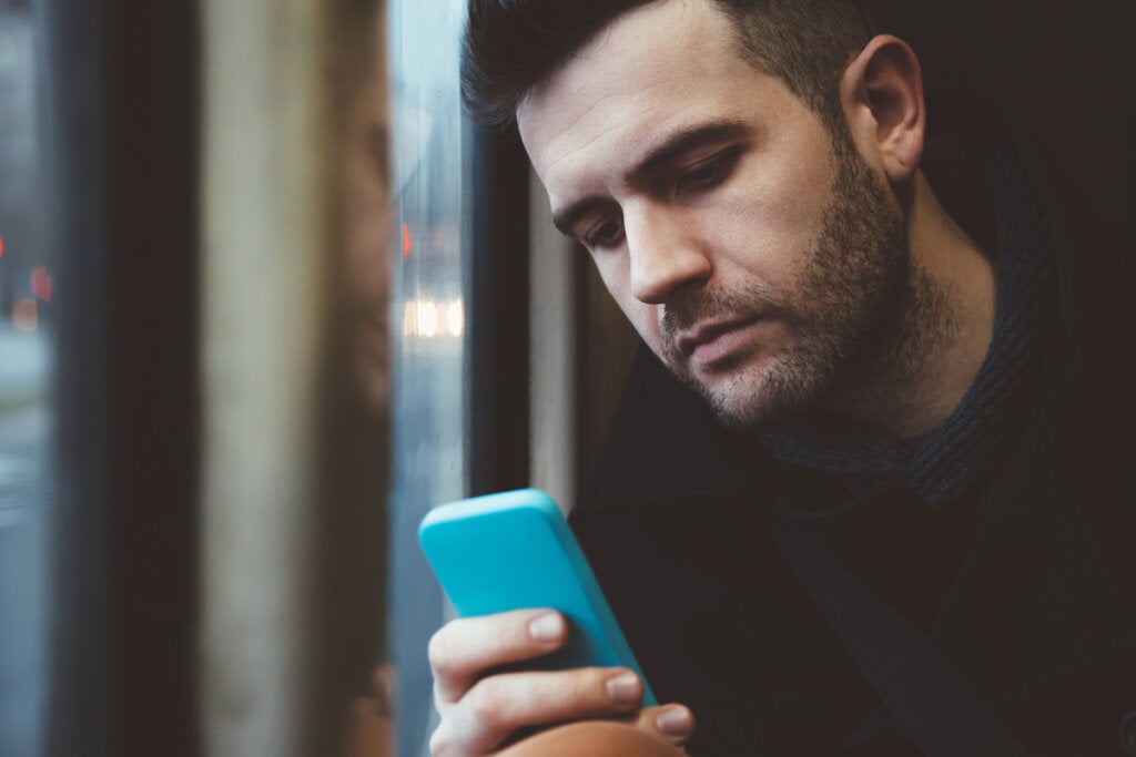 Homme triste regardant les notifications mobiles symbolisant l'effet de l'impuissance de l'information apprise