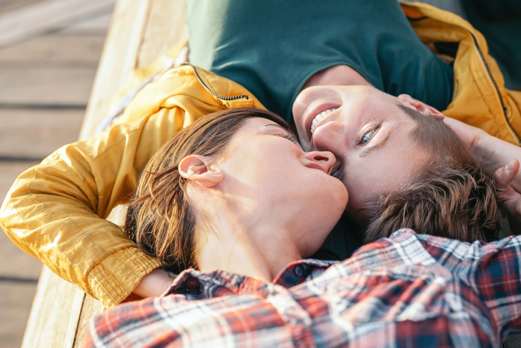 Couple lying on a bench looking at each other representing the difference between "I like" and "being in love"