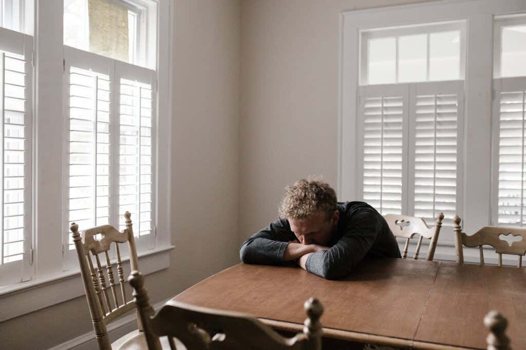 trieste man die in de eetkamer zit en lijdt aan een van de subtypes van ernstige depressie