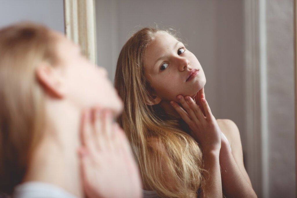 Chica adolescente mirándose en el espejo pensando en desarrollar su coeficiente intelectual somático