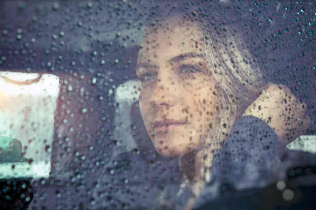 Frau denkt bei Regen an die Unvollkommenheit des Lebens
