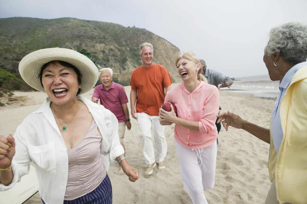 Glade seniorer på stranden, det motsatte av folk som eldes dårlig