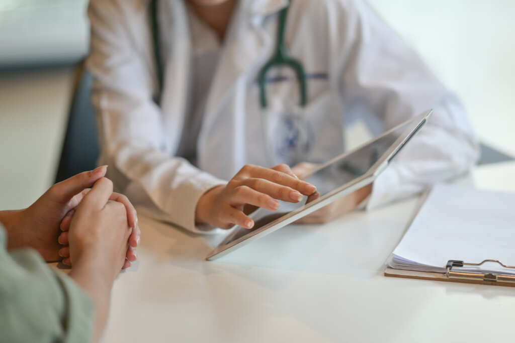 Médico con paciente hablado sobre el no poder levantarse de la cama