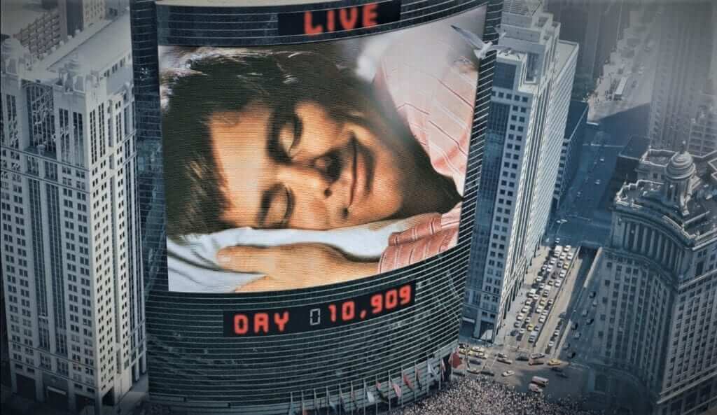 Vídeo de un hombre dormido proyectado en un edificio de la película el Show de Truman