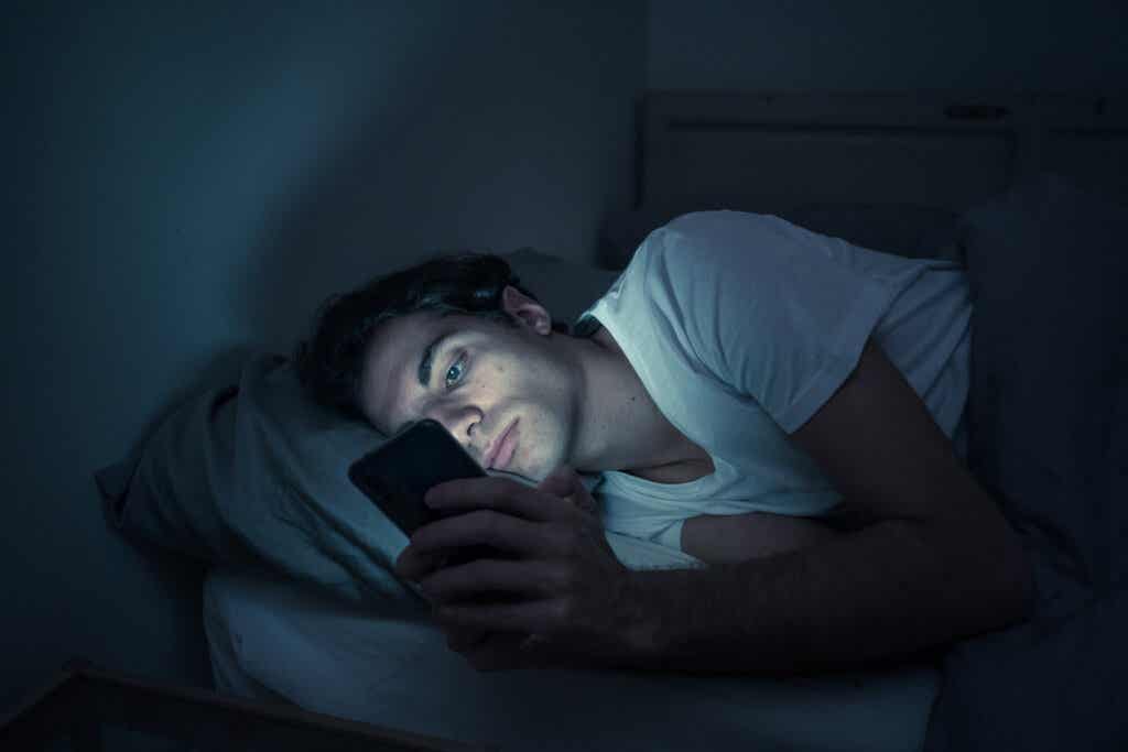 Jongen in bed kijkt naar zijn mobiel