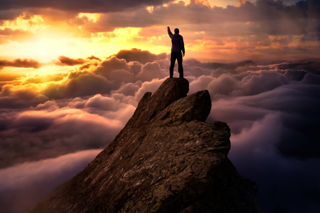 Hombre en la cima de una montaña pensando que hay que buscar la satisfacción