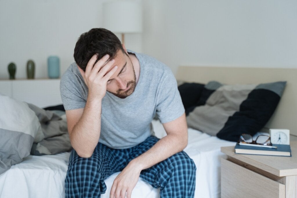 Un homme assis dans son lit pense que le stress nous vieillit