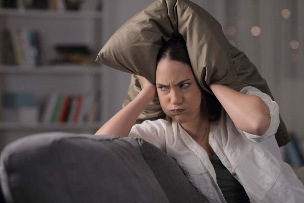 Donna arrabbiata che si copre la testa con un cuscino.