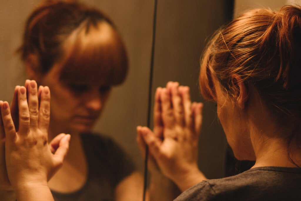 Rädd kvinna som ser sig själv i spegeln