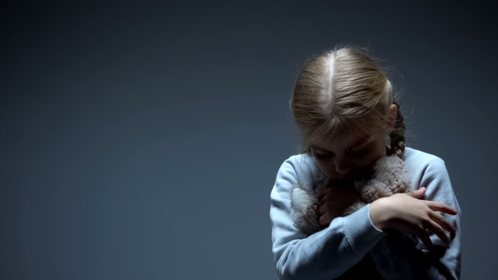 Niña triste abrazada a un peluche