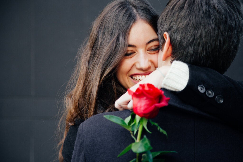 Mujer abrazando a su novio con una rosa