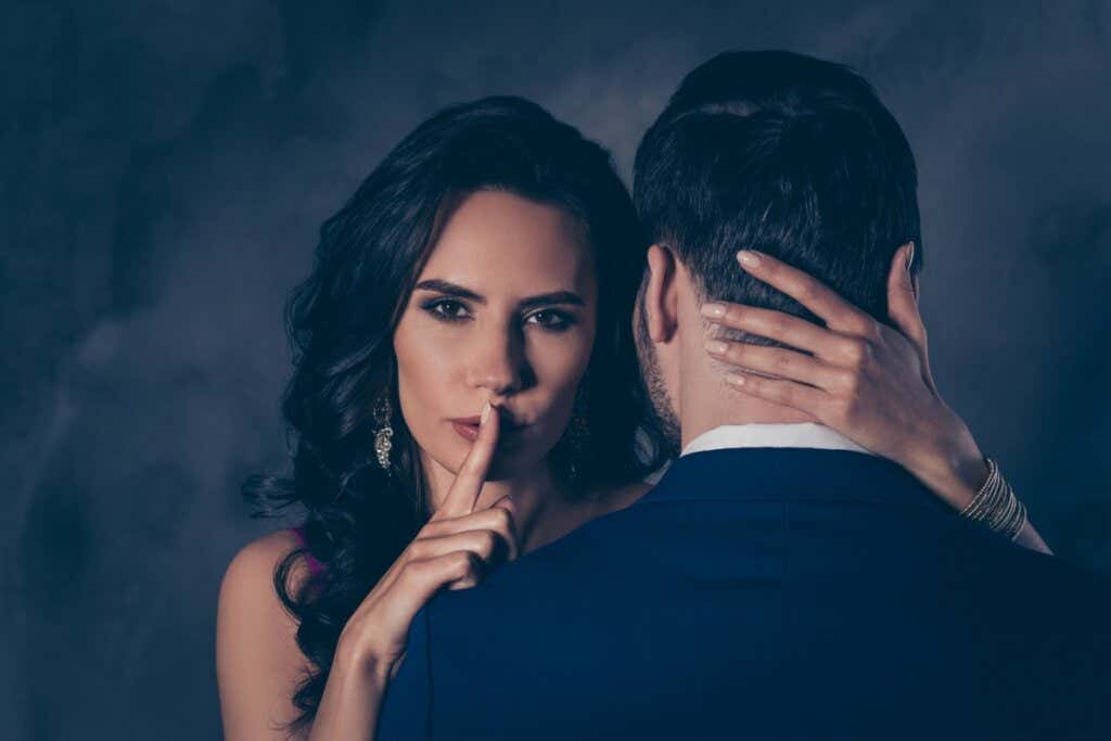 Vrouw omhelst man met vinger tegen haar lippen