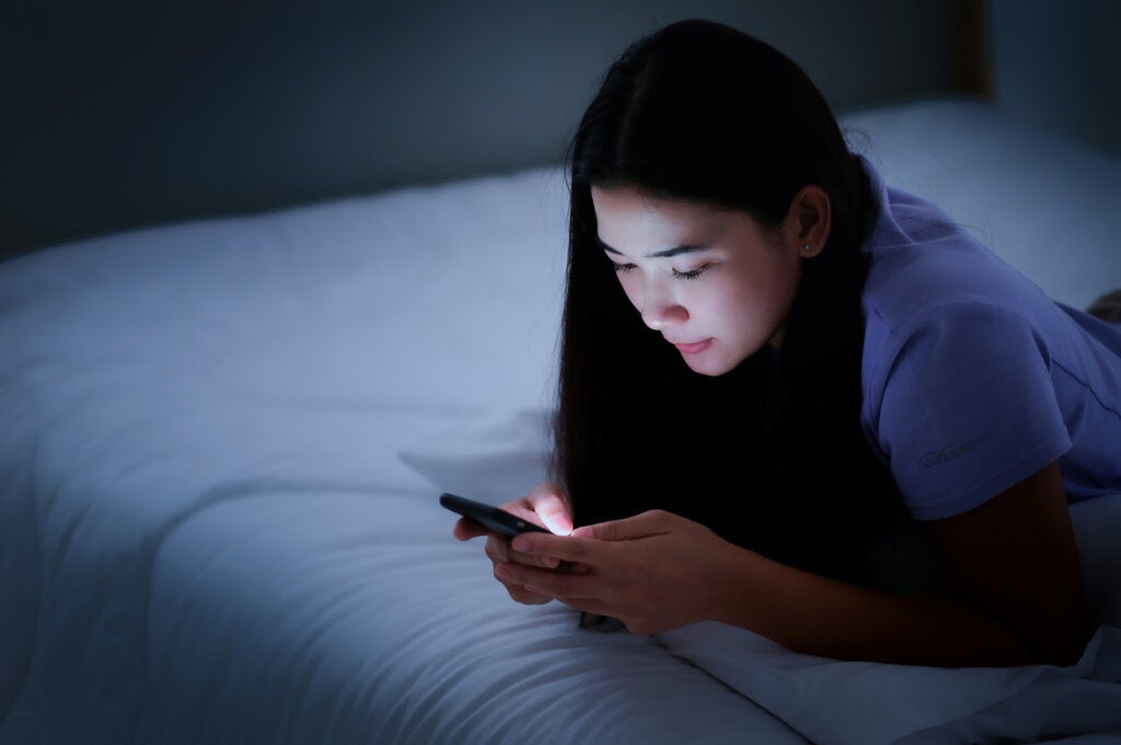 Tiener met haar mobieltje in bed