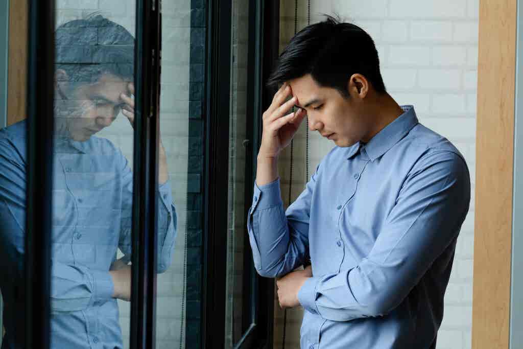 Hombre triste en la ventana pensando en cómo la depresión afecta a nuestro autoconcepto