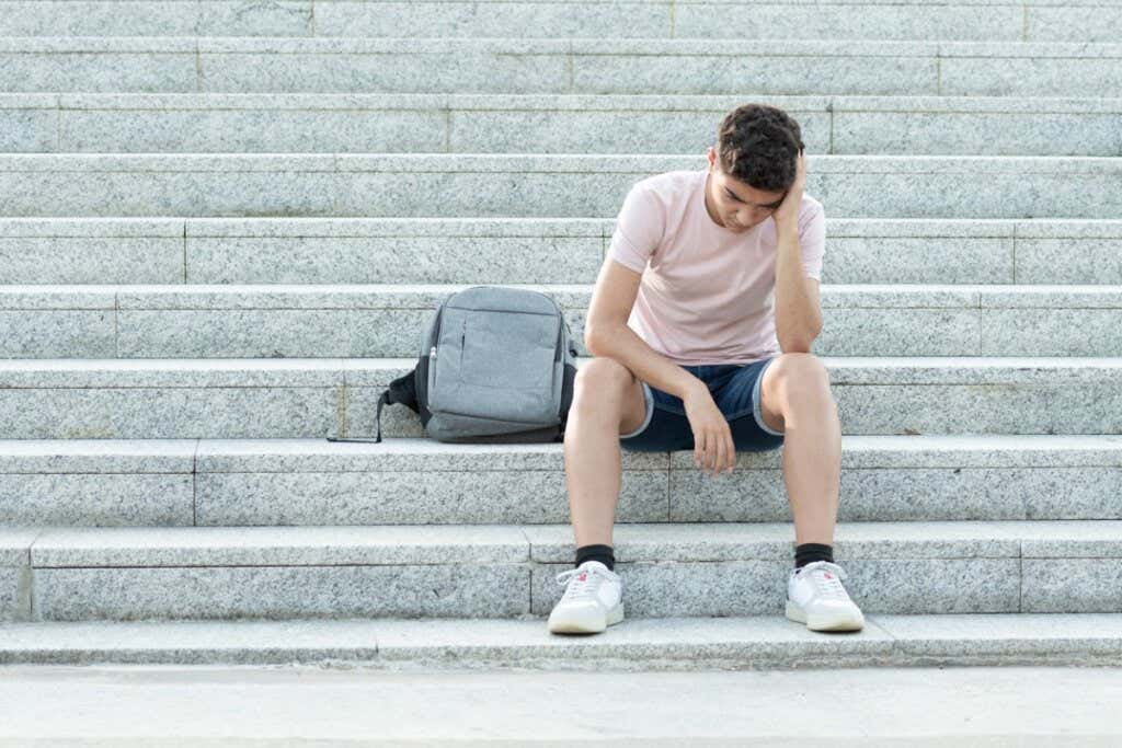 Chico que está sentado en unas escaleras representando a los jóvenes que no saben qué hacer con su vida