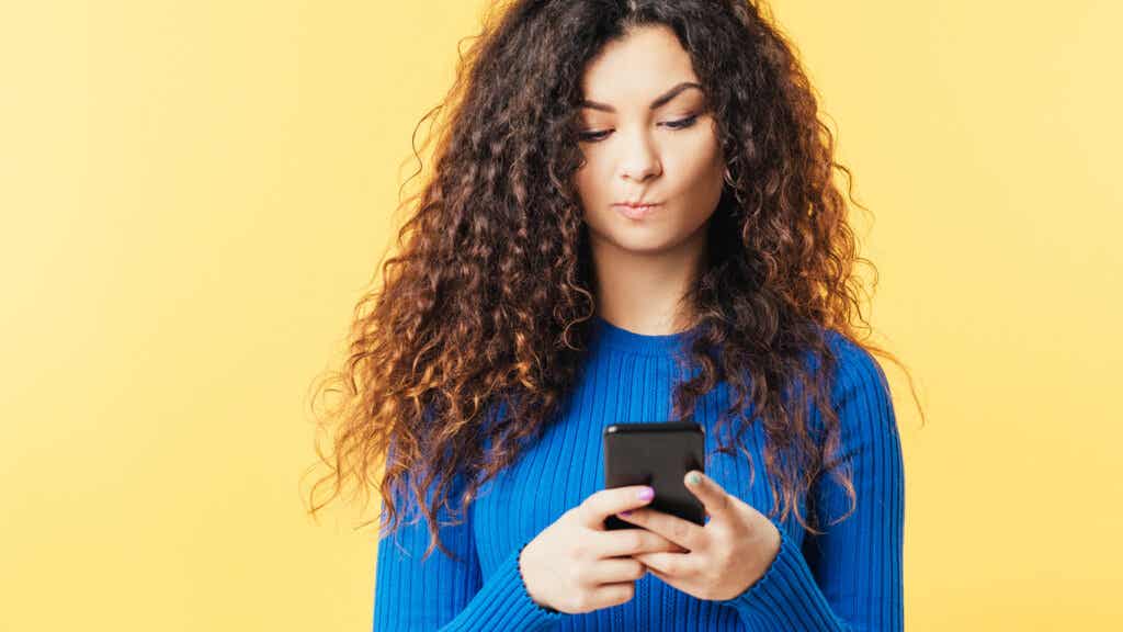 Kvinna som tittar på mobilen och tänker att människor inte längre är äkta