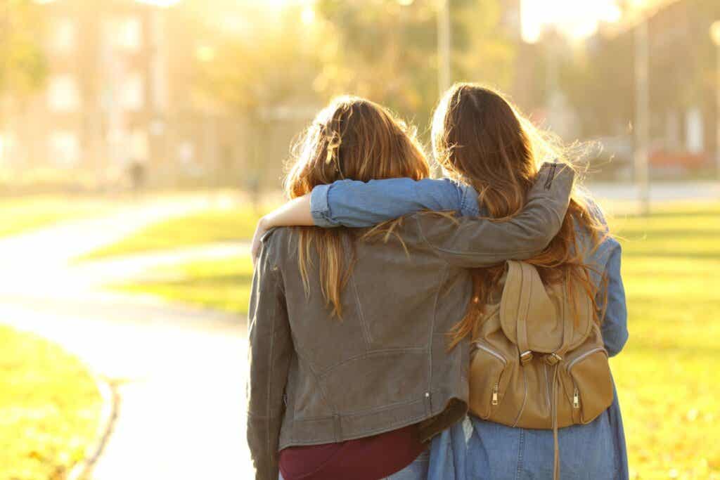 Dos amigas caminan abrazadas durante el atardecer