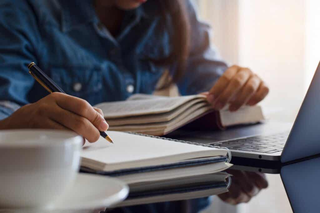 Mujer estudia con libro en mano y con su portátil por qué dejamos de aprender
