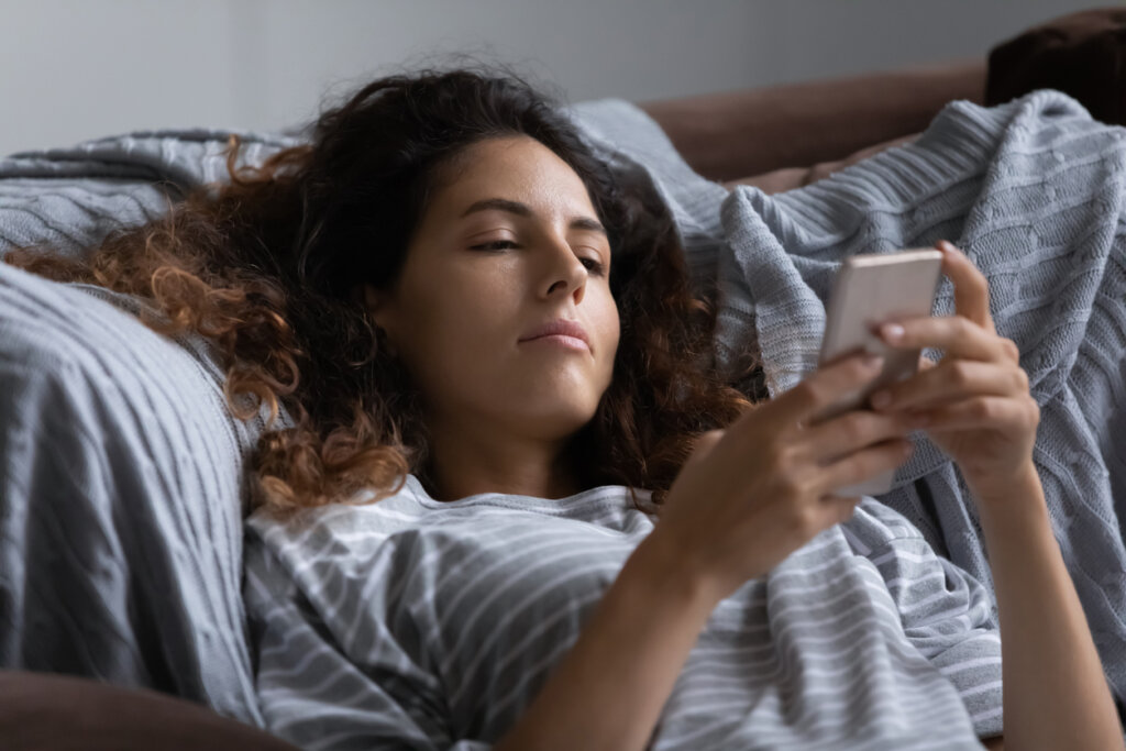 Mujer pensando en apagar el móvil antes de ir a dormir