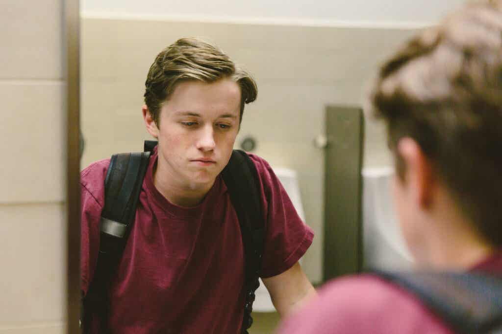 Trist tenåring ser seg i speilet