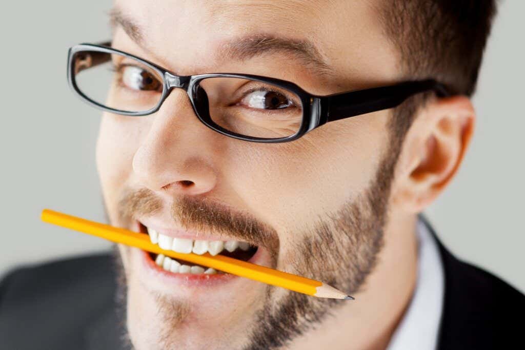 An executive has a pencil between his teeth