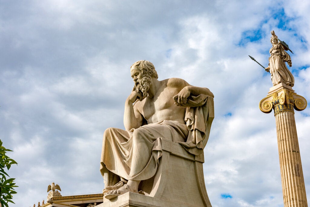 La estatua de Sócrates con la estatua de Athena detrás.