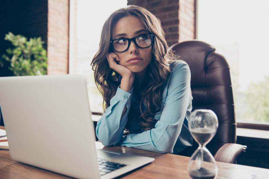 Bored woman at work thinking that it is not easy to do what you love