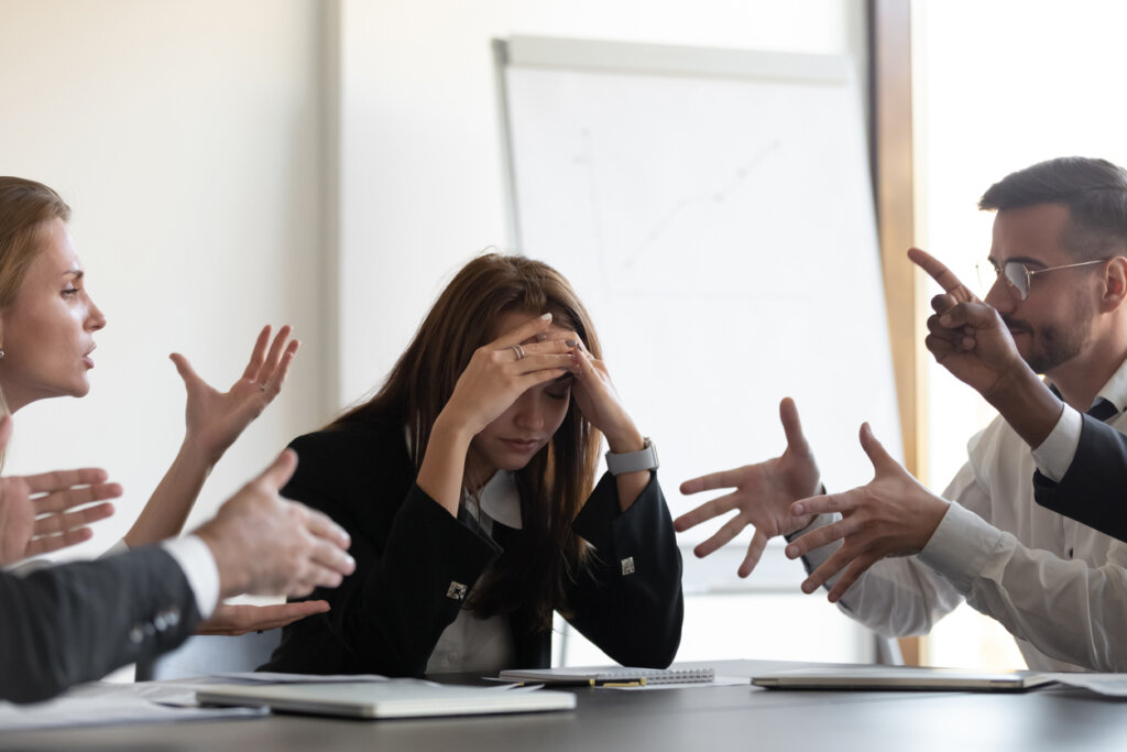 Mujer preocupada en reunión con personas de la oficina que discuten.