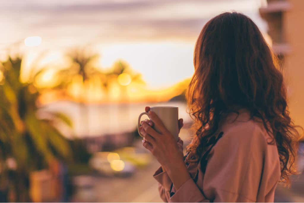 Donna che beve caffè al tramonto per rappresentare l'illusione dell'ipervalutazione