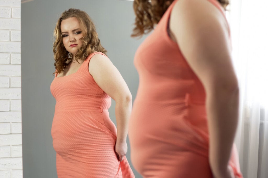Frau betrachtet sich im Spiegel und denkt an ihren BMI (Quetelet-Index)