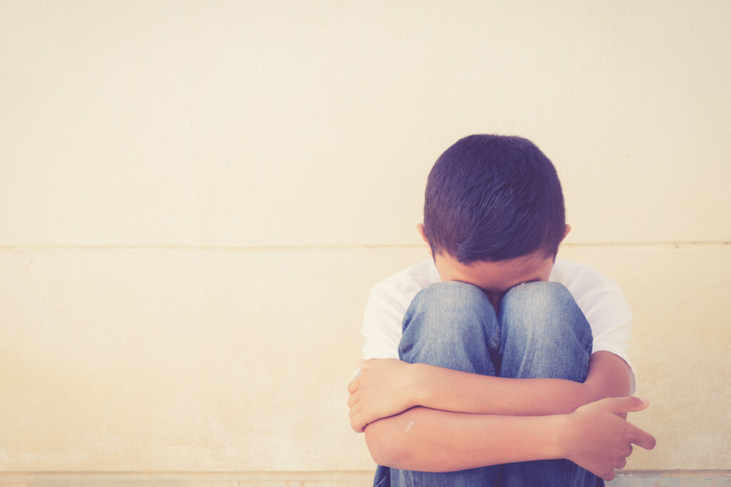 Niño con miedo sentado en el suelo