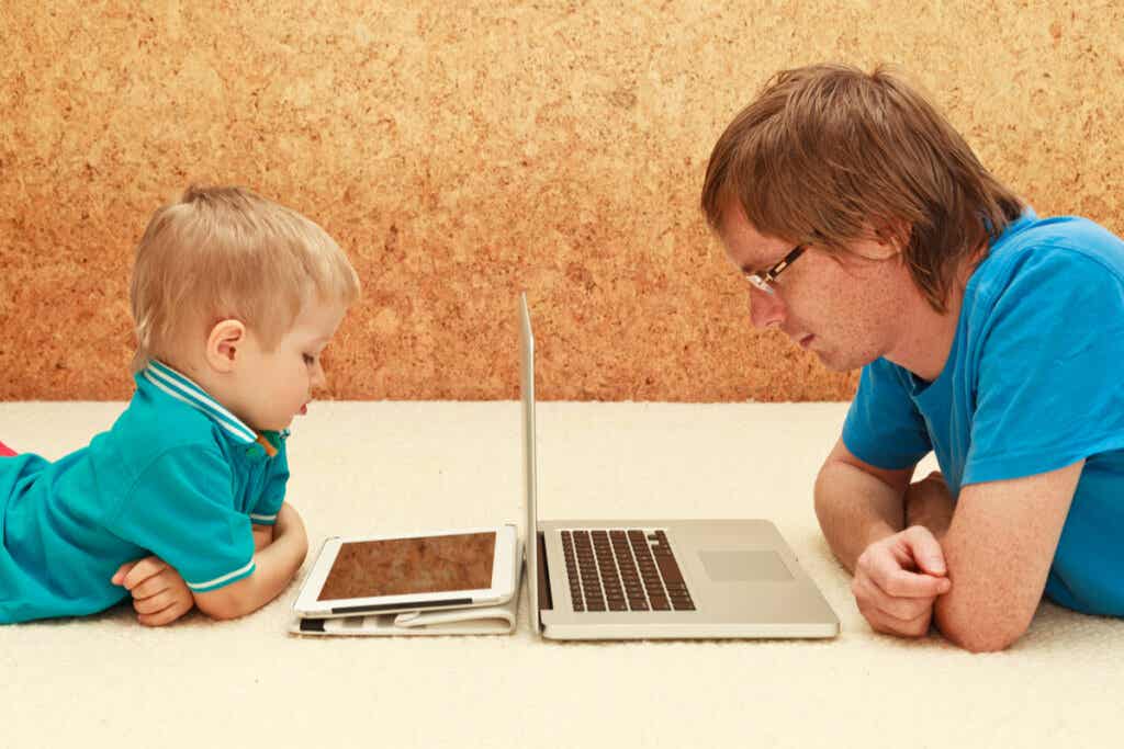 Bambino con un tablet e padre con un computer.