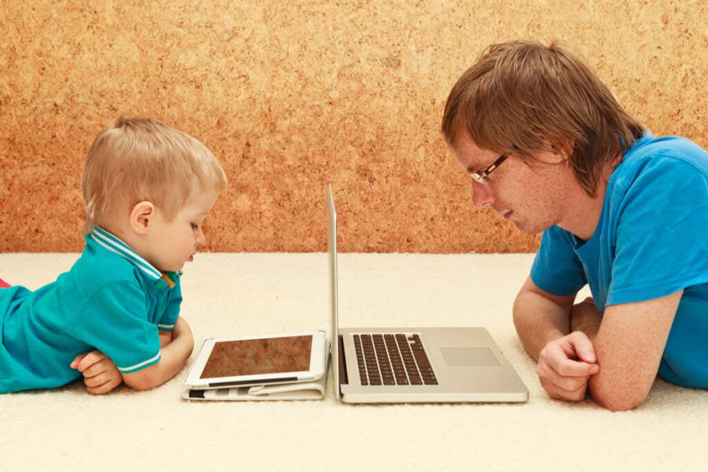 Gutt med nettbrett og far med datamaskin som symboliserer mobilavhengige foreldre