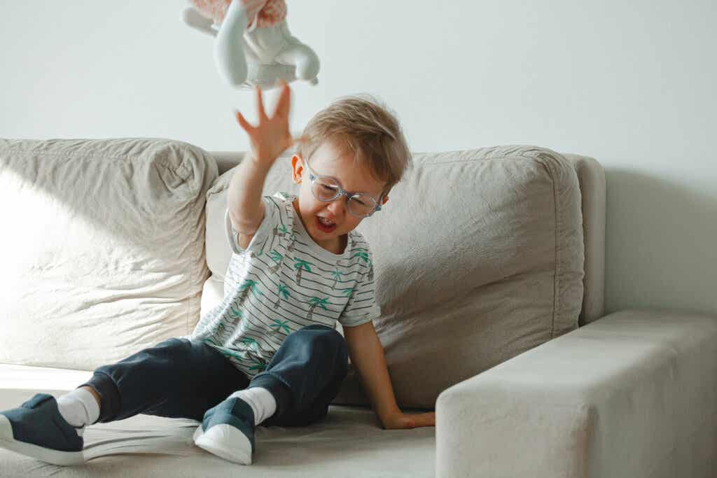 Niño tirando un muñeco en el sofá