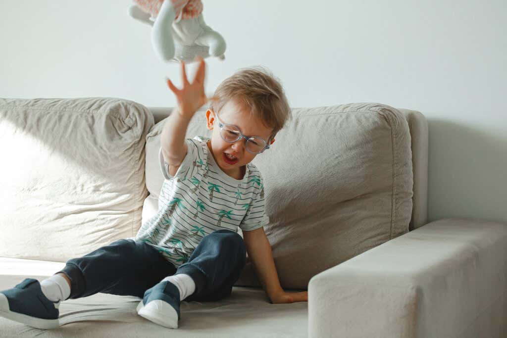 Chłopiec rzucający lalkę na sofę