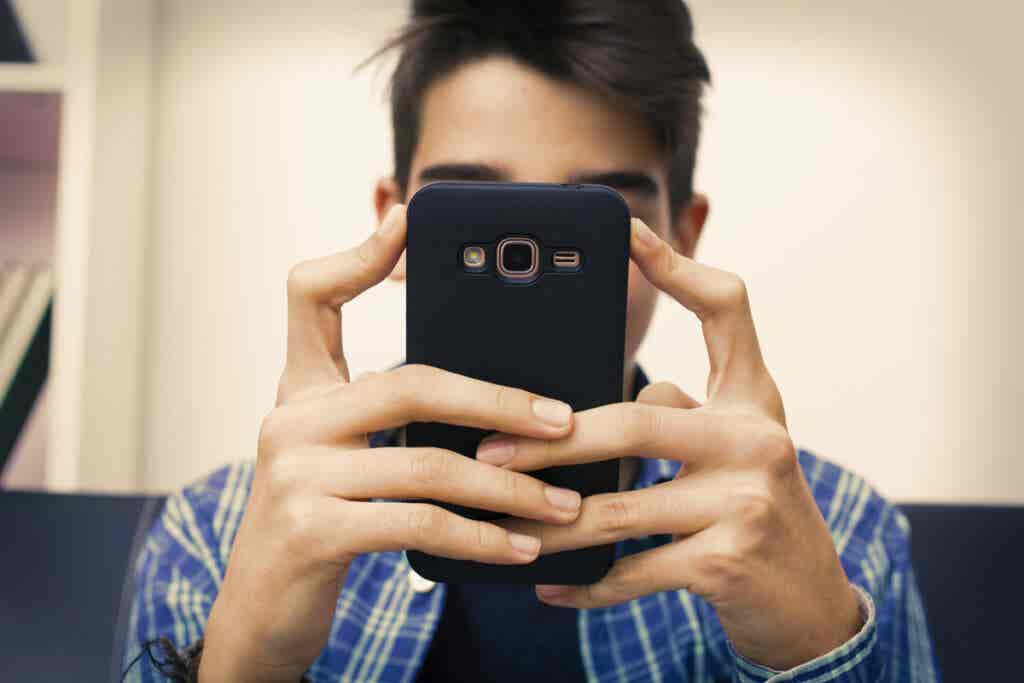 Adolescente con el móvil por adicción a las nuevas tecnologías