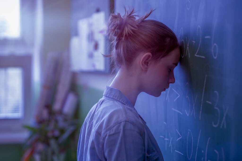 Adolescent pensant à la formule mathématique sur le tableau symbolisant la théorie de l'évitement cognitif de Borkovec