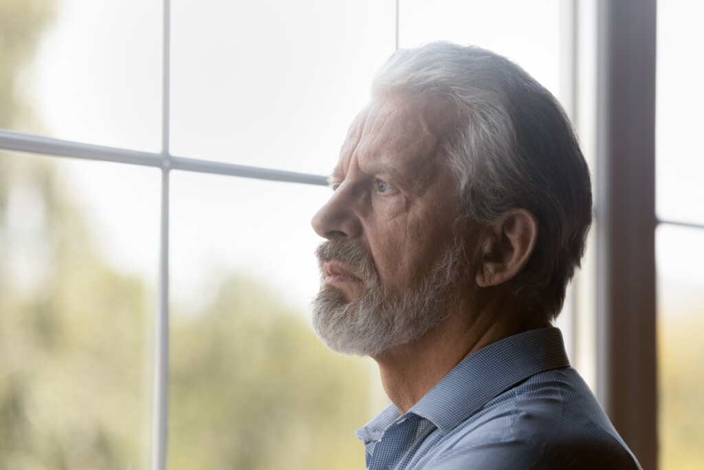 Homem olhando pela janela ouvindo as mentiras que a depressão nos conta