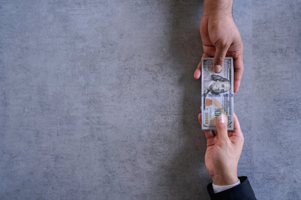 Main d'un homme donnant de l'argent à un autre