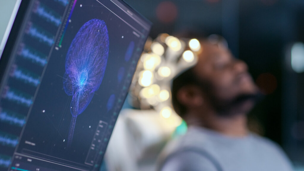 Monitores exibem modelo cerebral gráfico e leitura de EEG simbolizando neurotecnologias