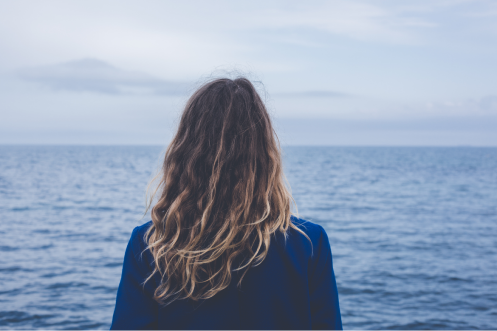 Frau blickt aufs Meer und denkt an die Unvollkommenheit des Lebens