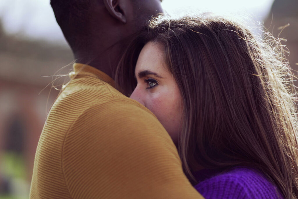Mujer pensando mientras su novio la abraza
