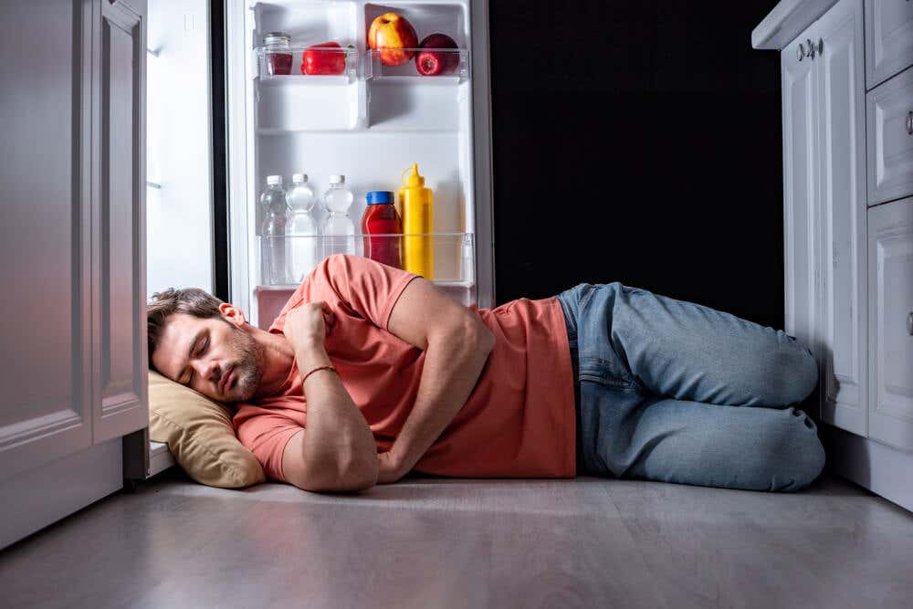 Uomo che dorme con il frigorifero aperto.