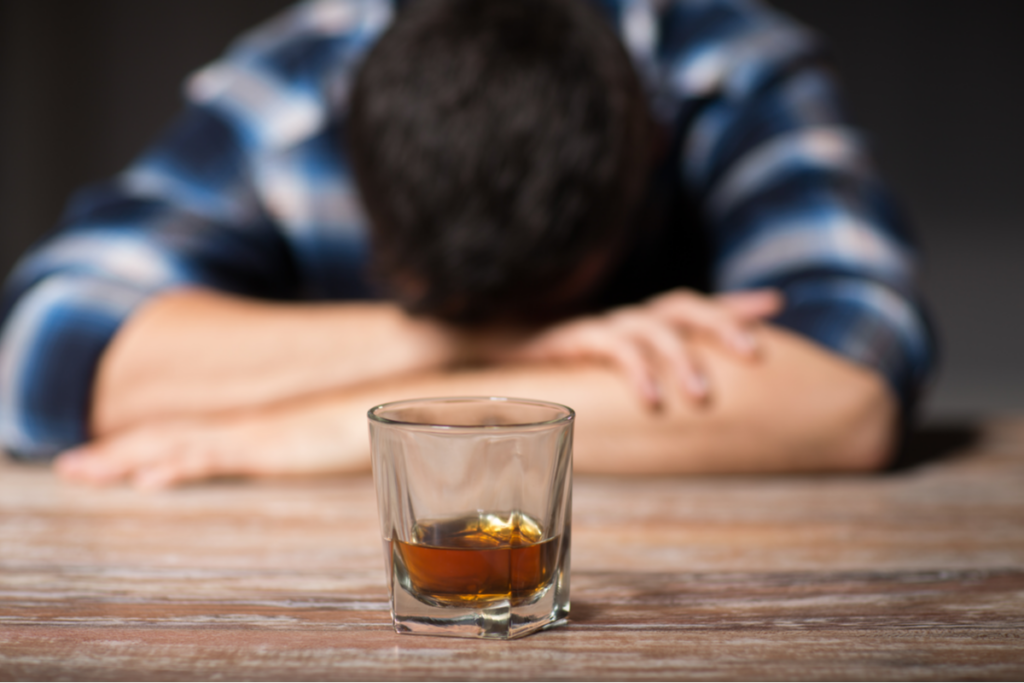 Uomo con un bicchiere di alcol che simboleggia che bere alcolici non migliora lo umore.